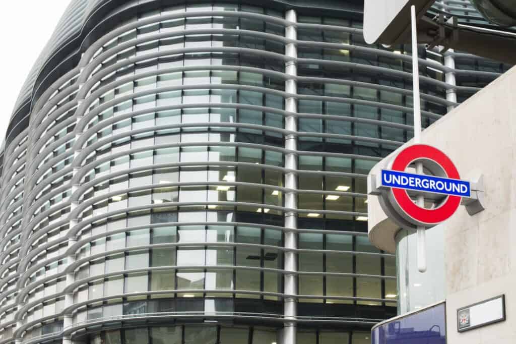 A subway station sign beside a huge building