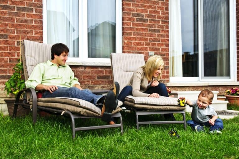 A happy family is relaxing in their backyard in the concept of settling in their new home.