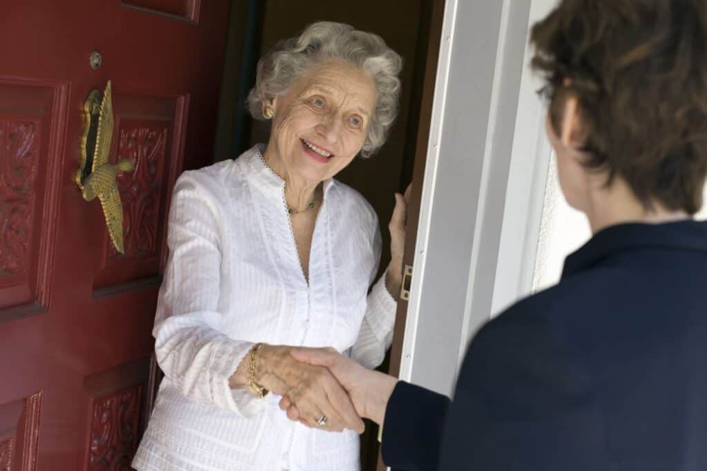 A senior lady is meeting her new neighbour by the door.