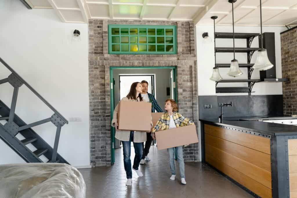 A family has arrived in their new apartment, carrying cardboard boxes, in the concept of relocating to Ilford.