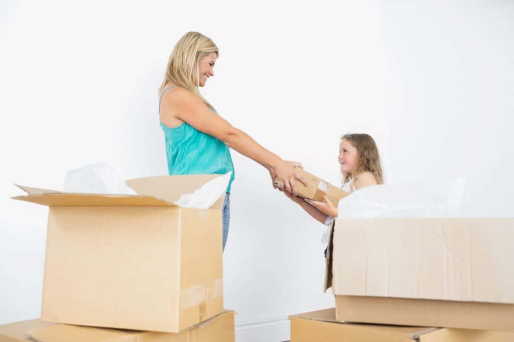 A mother and daughter are surrounded by boxes upon moving in.