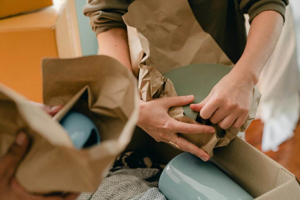 A woman is packing delicate items into a carton