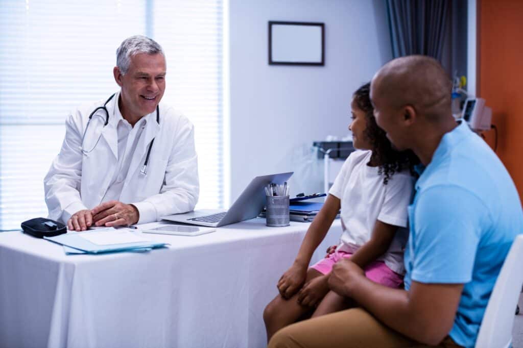 A paediatrician interacting with a patient and parent in a paediatric clinic