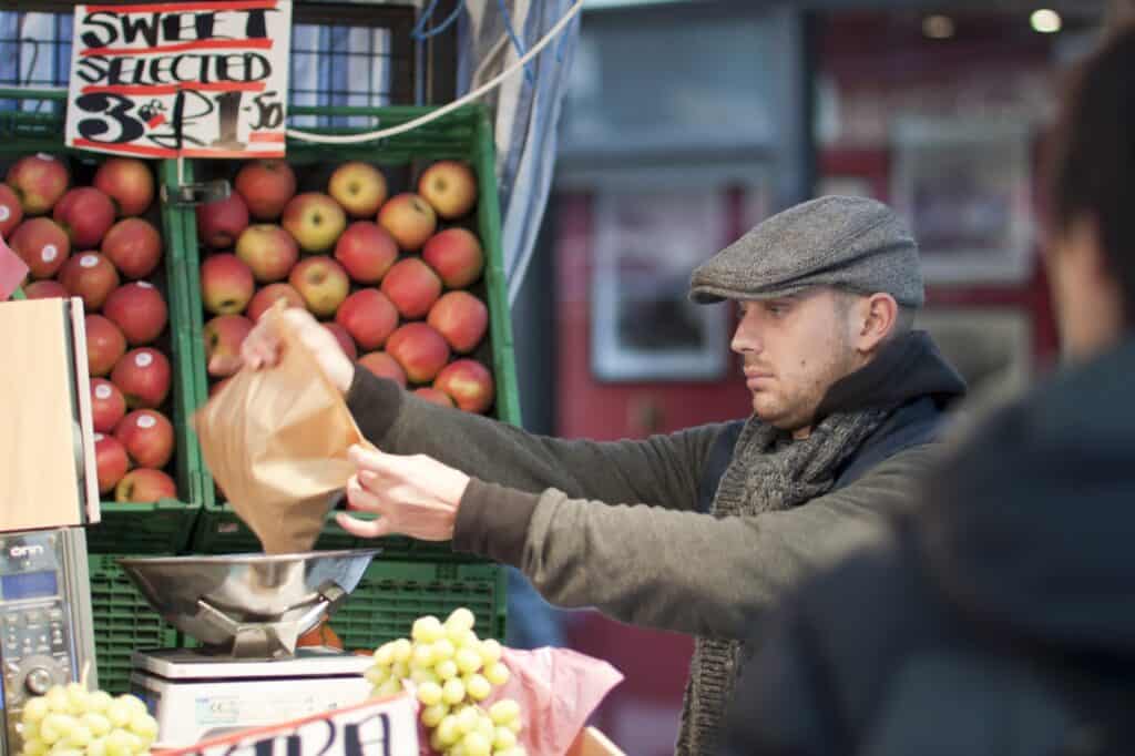 A fruit seller is wrapping fruits for the buyer in the concept of local shops and markets in Ilford.