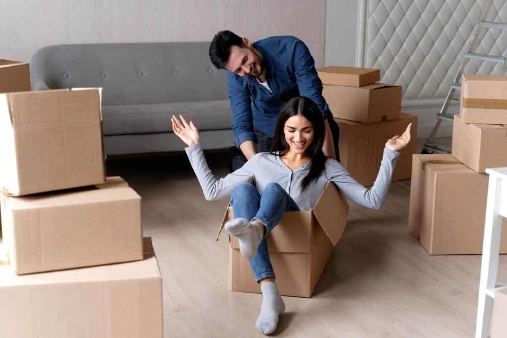 A happy couple playing with a box after the stress-free move